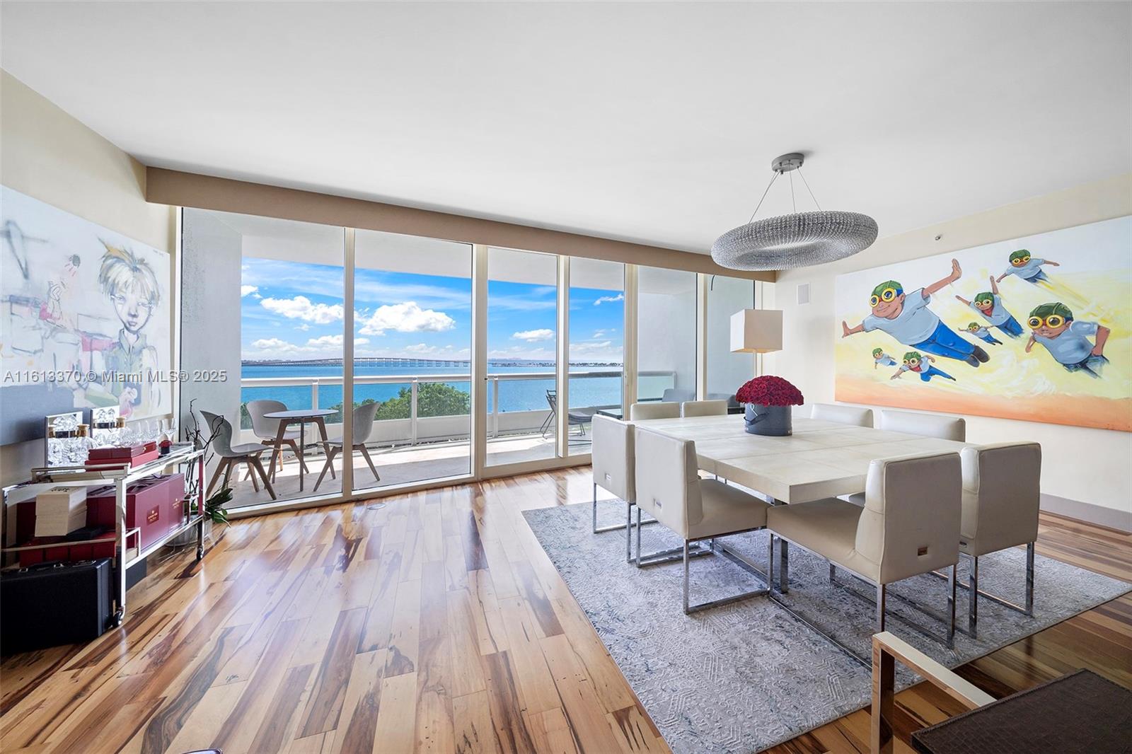 A dining room features a large table, modern chairs, hardwood floors, and a balcony view — 1643 Brickell Ave # 704, Miami FL 33129, MIAMI, FL