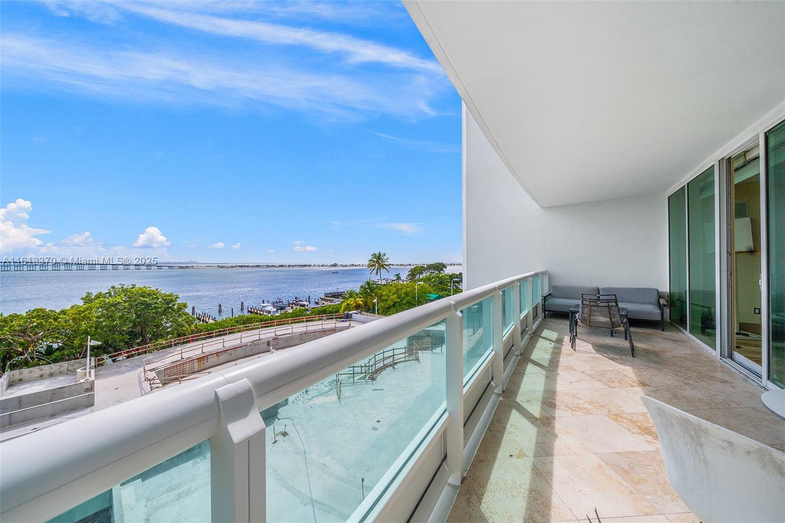 A balcony with stone flooring overlooks a bay, a marina, and a bridge — 1643 Brickell Ave # 704, Miami FL 33129, MIAMI, FL
