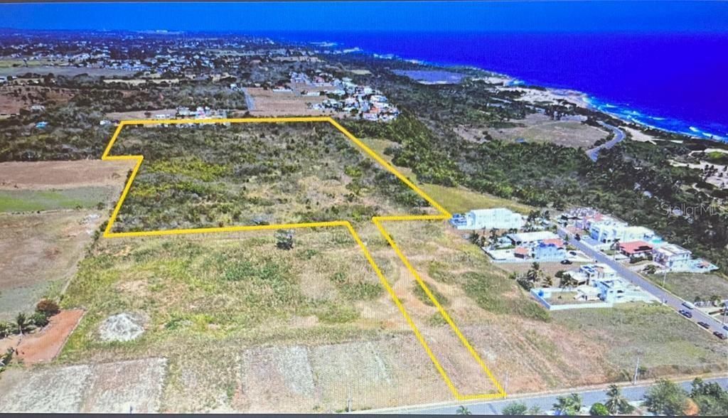 An aerial view shows a large, undeveloped plot of land outlined in yellow near the coast — CALLE MANUELA LAMELA ABREU STREET, ISABELA, PR