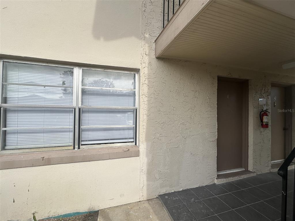 An exterior view of a building entrance with a window, a door, and a fire extinguisher — 1912 HONOUR ROAD UNIT 1, ORLANDO, FL