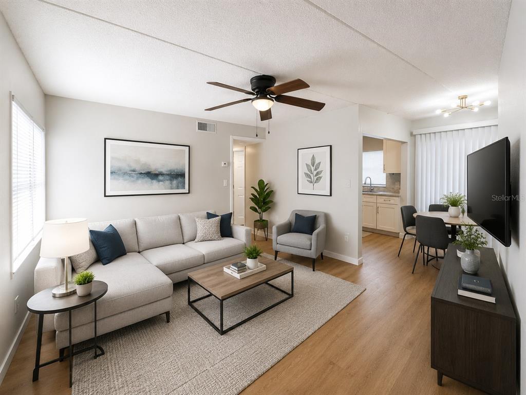 A living room with a sectional sofa, coffee table, armchair, and an adjacent dining area — 1912 HONOUR ROAD UNIT 1, ORLANDO, FL