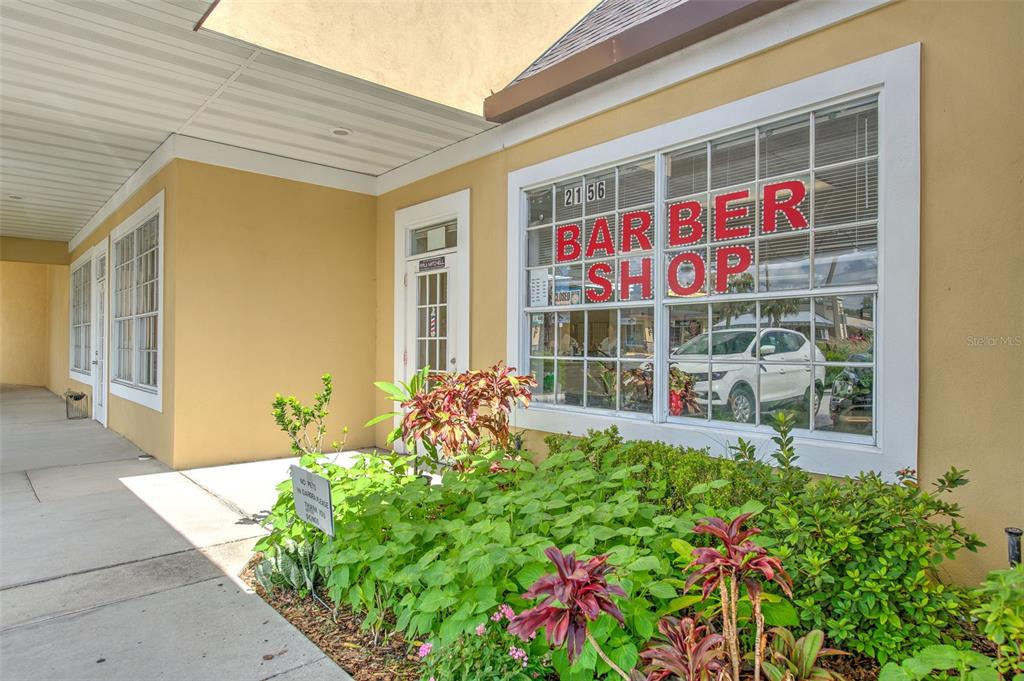 An exterior view of a barber shop storefront with a large window and landscaping — 2156 CO RD 540A, LAKELAND, FL