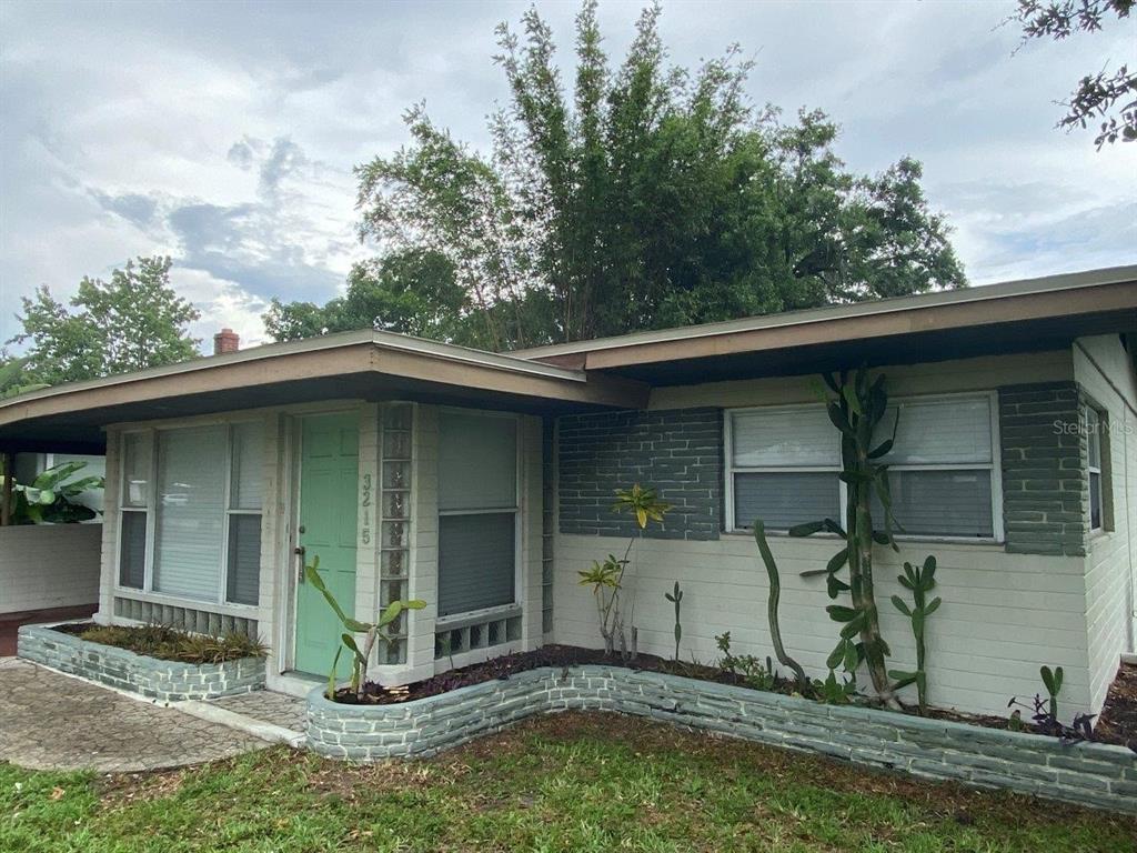 A single-story house exterior features a light green door, brick accents, and a front garden — 3215 N ORANGE AVENUE, ORLANDO, FL