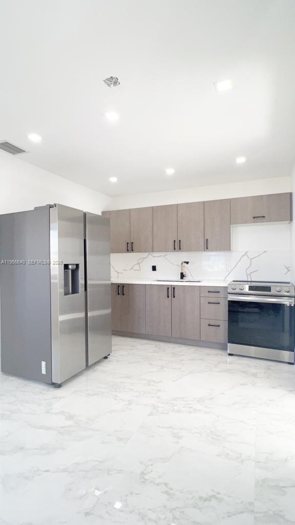 A modern kitchen features light wood cabinets, stainless steel appliances, and white marble-patterned flooring — 1013 NW 1st Ave, Hallandale Beach FL 33009, HALLANDALE BEACH, FL