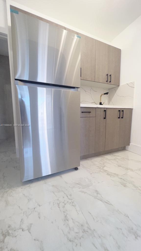 A stainless steel refrigerator stands next to light wood cabinets and a marble-patterned countertop — 1013 NW 1st Ave, Hallandale Beach FL 33009, HALLANDALE BEACH, FL