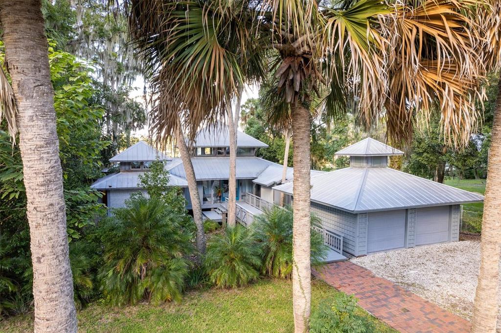 An elevated view of a gray house with metal roofs surrounded by palm trees — 25608 DEVONIA STREET, MELROSE, FL