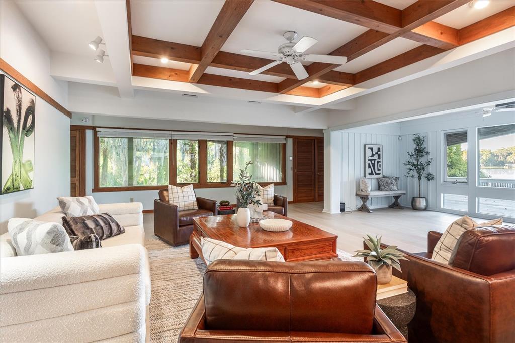 A living room features a coffered wood ceiling, leather armchairs, and large windows overlooking water — 25608 DEVONIA STREET, MELROSE, FL