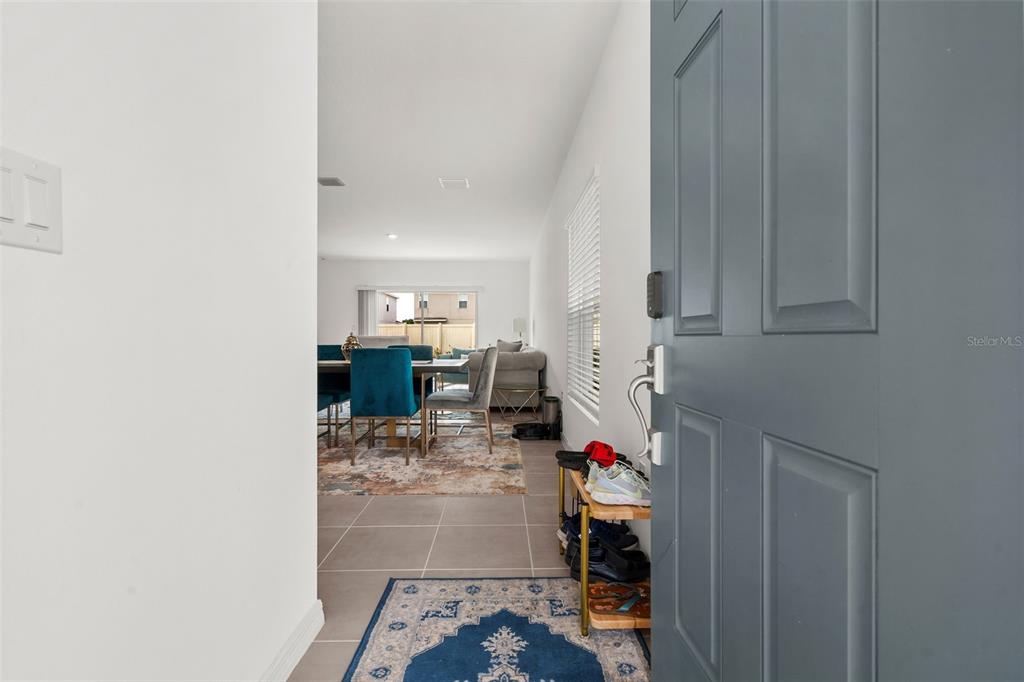 An entryway with a blue door leads to an open-concept dining and living area — 6434 MILESTONE LOOP, PALMETTO, FL