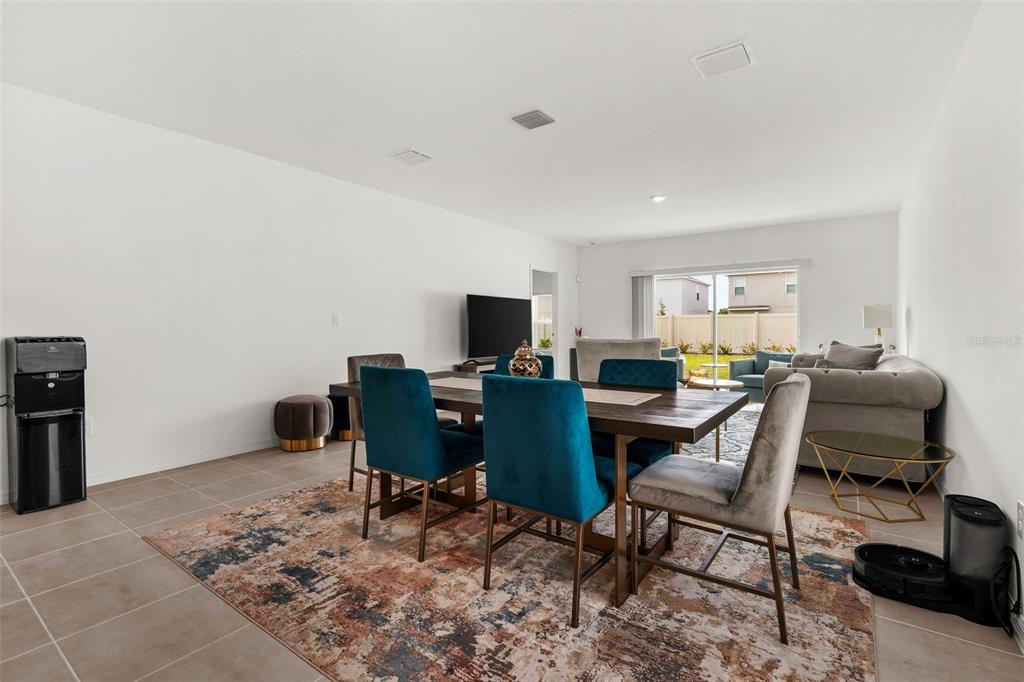 A dining area with a wooden table, blue chairs, and a rug on tile flooring — 6434 MILESTONE LOOP, PALMETTO, FL