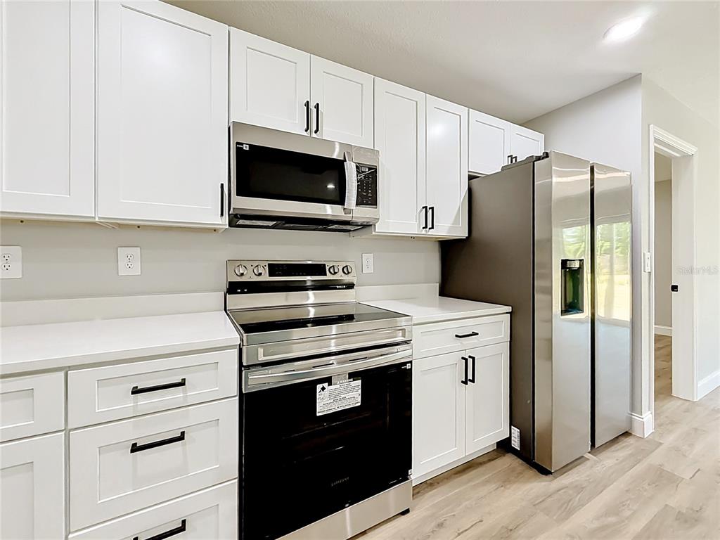 A kitchen features white cabinets, stainless steel appliances, and light-colored countertops — 6 CEDAR TRACE COURT, OCALA, FL