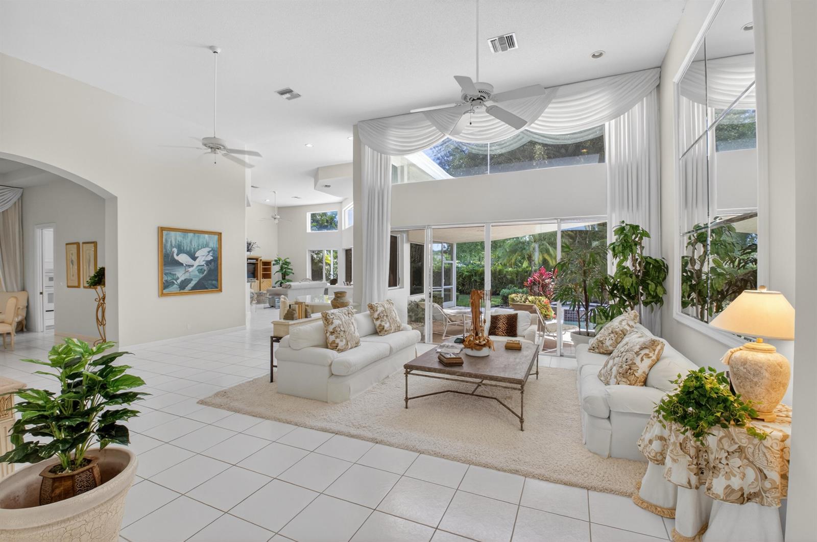 A bright, open-concept living room features white tile floors, high ceilings, and large glass doors — 21650 Frontenac Court, Boca Raton FL 33433, BOCA RATON, FL