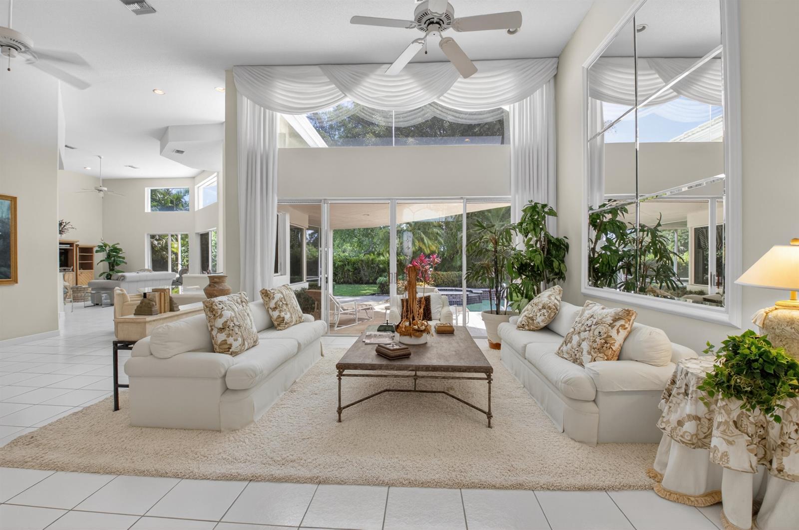 A bright living room features two white sofas, a coffee table, and large glass doors — 21650 Frontenac Court, Boca Raton FL 33433, BOCA RATON, FL