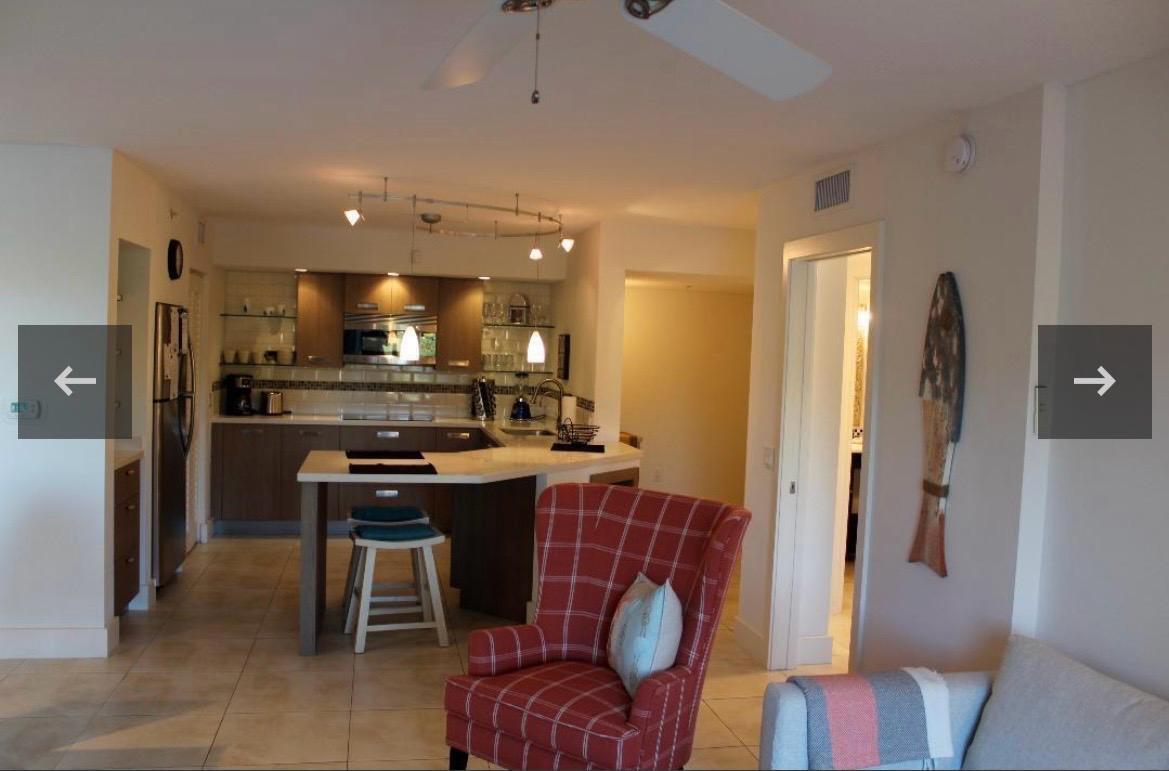 A kitchen with wood cabinets and a breakfast bar sits behind a red plaid chair — 808 Villa Circle, Boynton Beach FL 33435, BOYNTON BEACH, FL