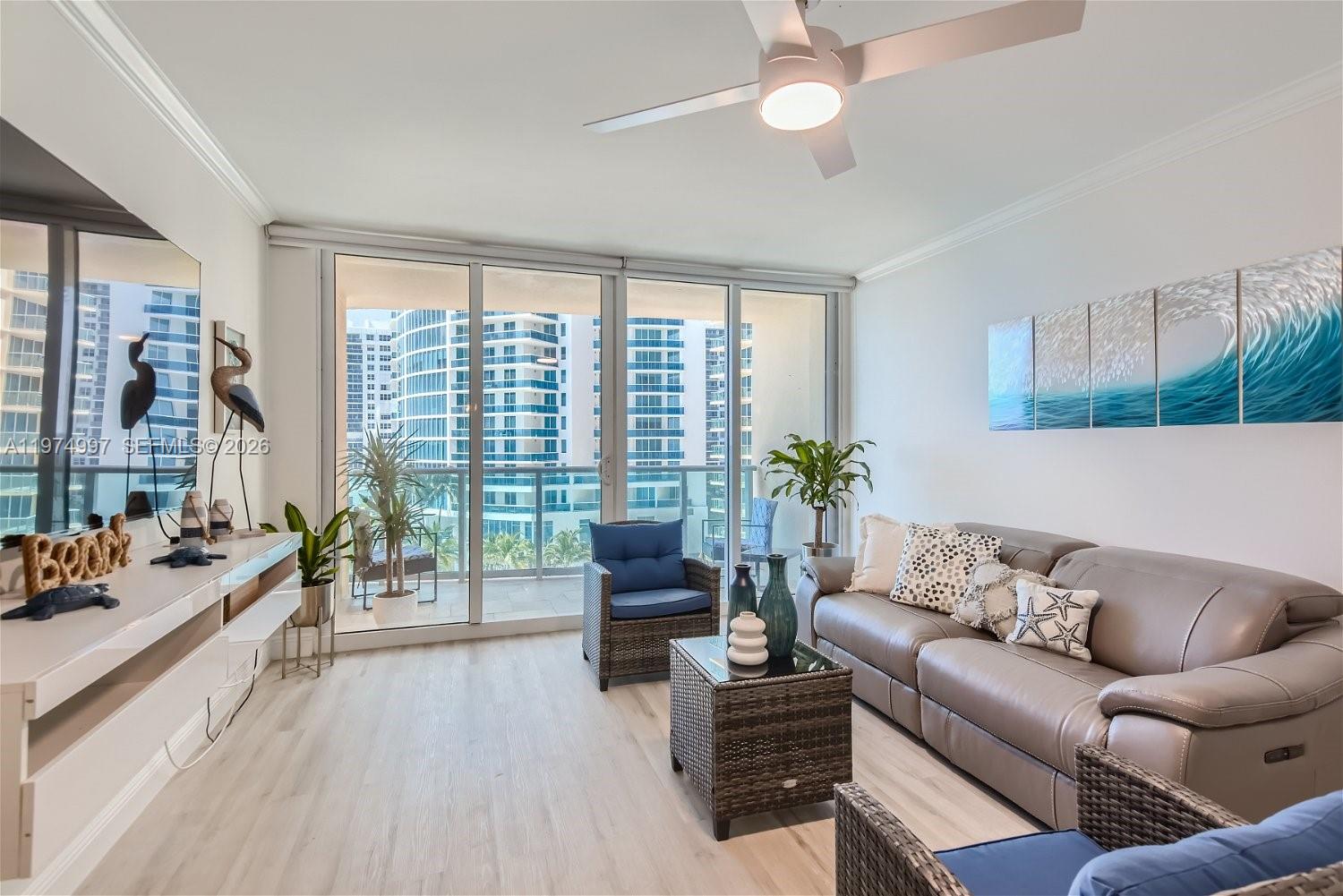 A living room features light wood flooring, a leather sofa, and floor-to-ceiling balcony windows — 2501 S Ocean Dr, Hollywood FL 33019, HOLLYWOOD, FL