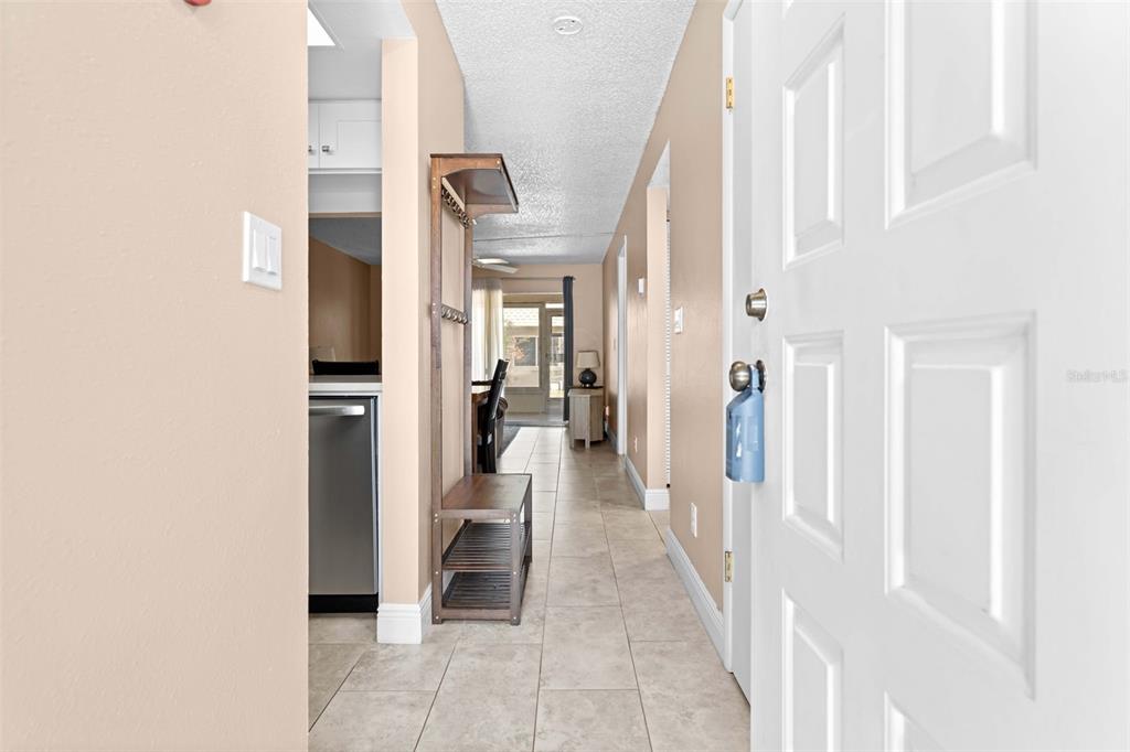 A view from an open doorway looking down a tiled hallway toward a living area — 3534 TEESIDE DRIVE, NEW PORT RICHEY, FL