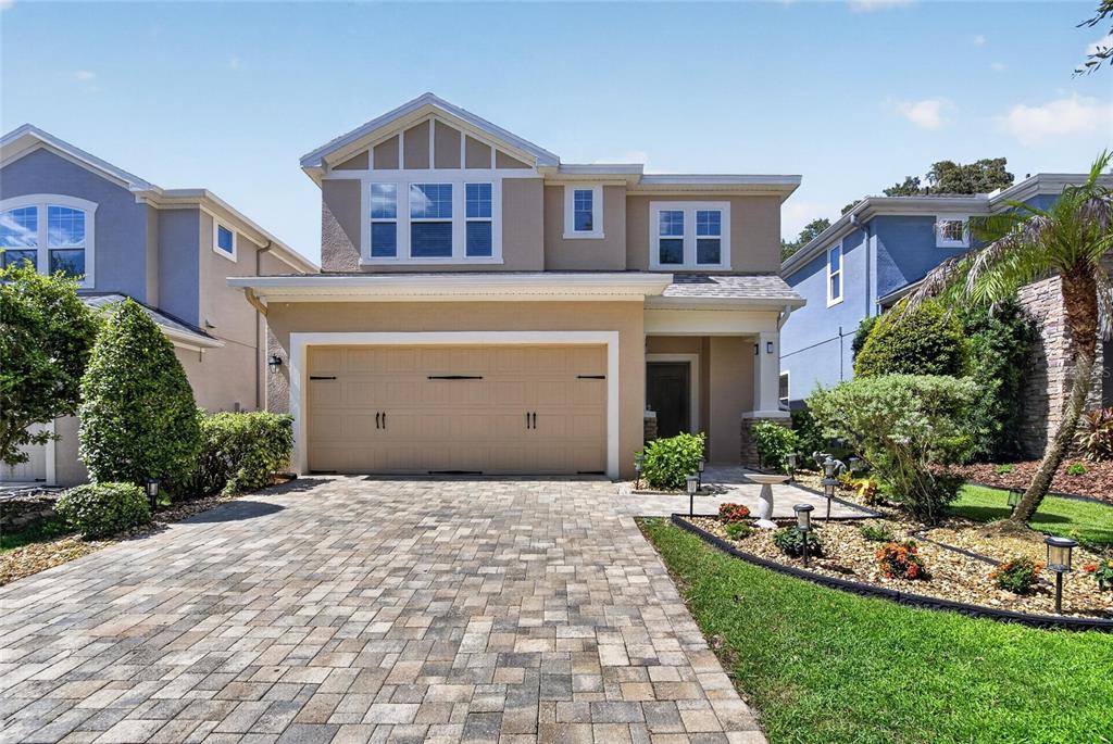 A two-story house with a tan stucco exterior, a paved driveway, and a two-car garage — 16220 BAYBERRY VIEW DRIVE, LITHIA, FL
