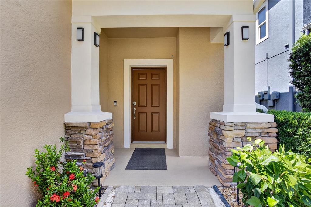 The front entrance features a brown door, stone-based columns, and a paved walkway — 16220 BAYBERRY VIEW DRIVE, LITHIA, FL