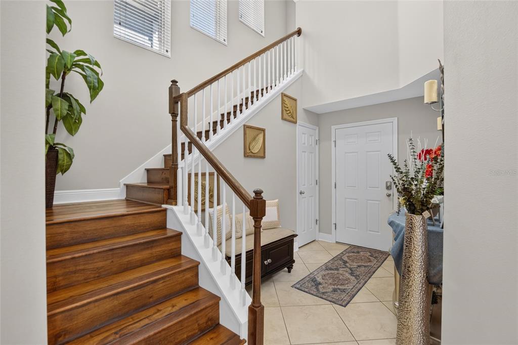 An entryway features a wooden staircase, tile flooring, a white front door, and a bench — 16220 BAYBERRY VIEW DRIVE, LITHIA, FL