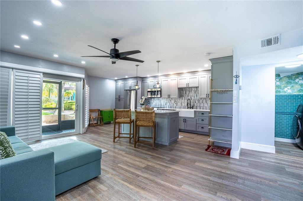 A kitchen with gray cabinetry and an island opens to a living area with flooring — 1005 S BAYSHORE BOULEVARD UNIT 102, SAFETY HARBOR, FL