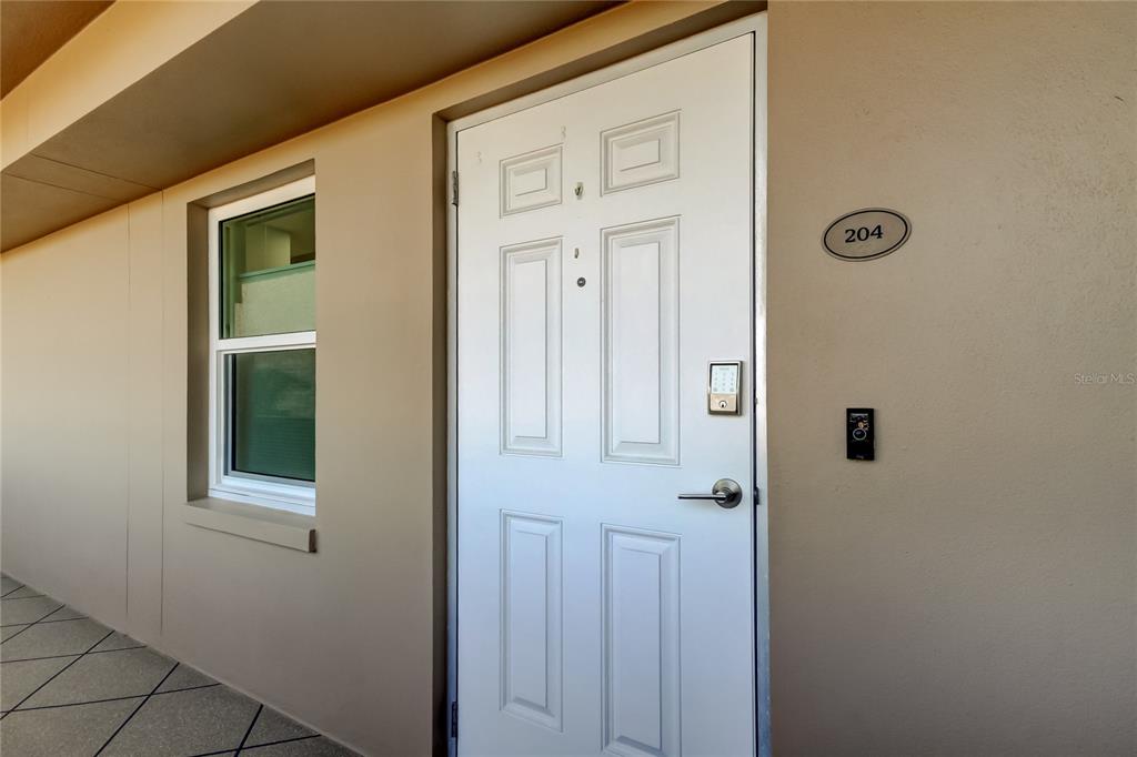 A white exterior door with a digital lock and the number 204 beside it — 5200 BRITTANY DRIVE S UNIT 204, ST PETERSBURG, FL