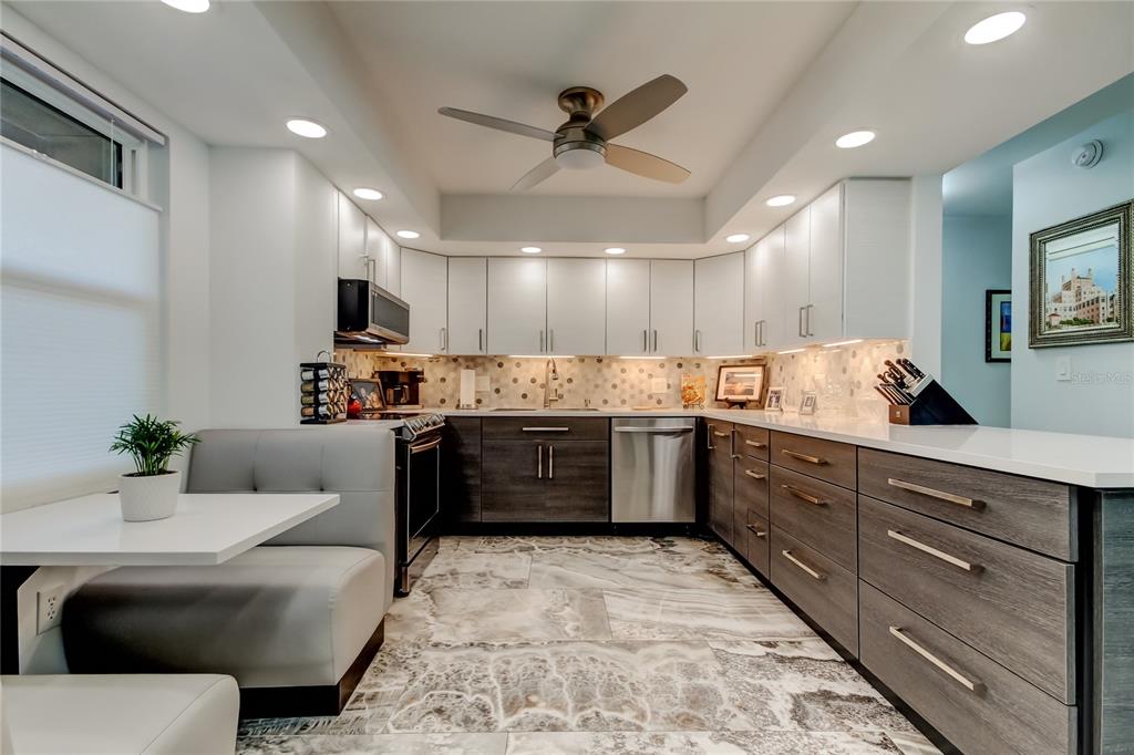 A modern kitchen features two-toned cabinetry, stainless steel appliances, and a built-in dining booth — 5200 BRITTANY DRIVE S UNIT 204, ST PETERSBURG, FL