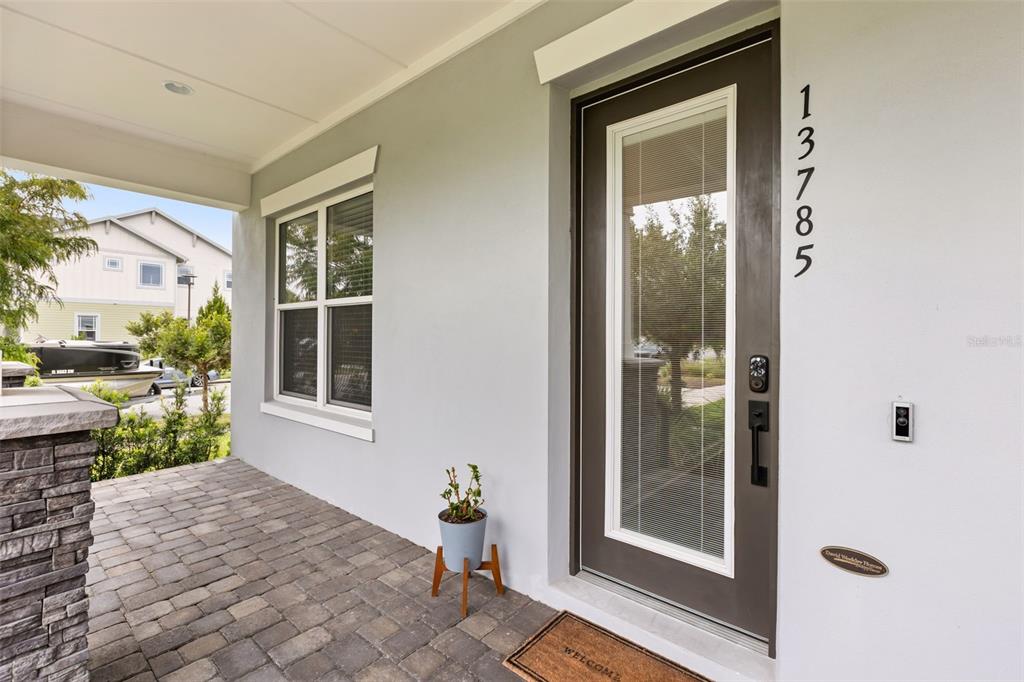A gray front door with a glass insert and house numbers sits on a paved porch — 13785 BEHRING AVENUE, ORLANDO, FL