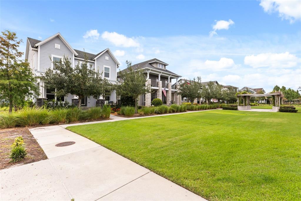 A row of multi-story houses faces a large grassy lawn with a wooden pergola — 13785 BEHRING AVENUE, ORLANDO, FL