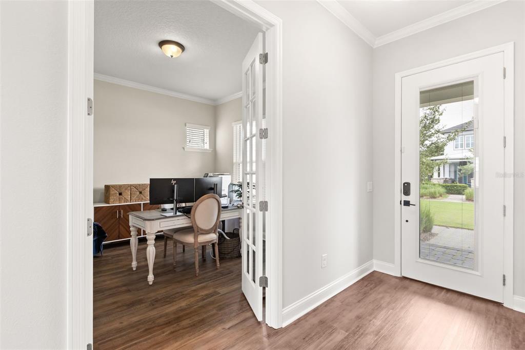 A home office with French doors is visible from a bright entryway with wood flooring — 13785 BEHRING AVENUE, ORLANDO, FL