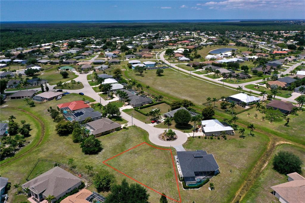 An aerial view shows a vacant residential lot outlined in red next to a house — 204 YELLOW ELDER, PUNTA GORDA, FL