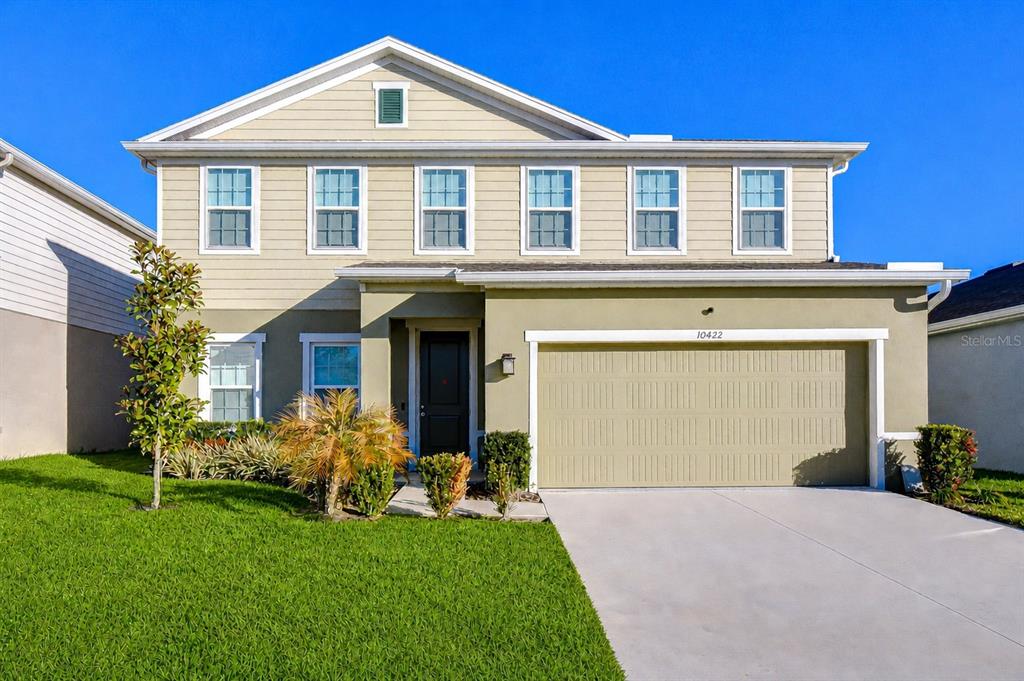 A two-story house with beige siding, a green lower level, and a two-car garage — 10422 GLIDING EAGLE WAY, LAND O LAKES, FL