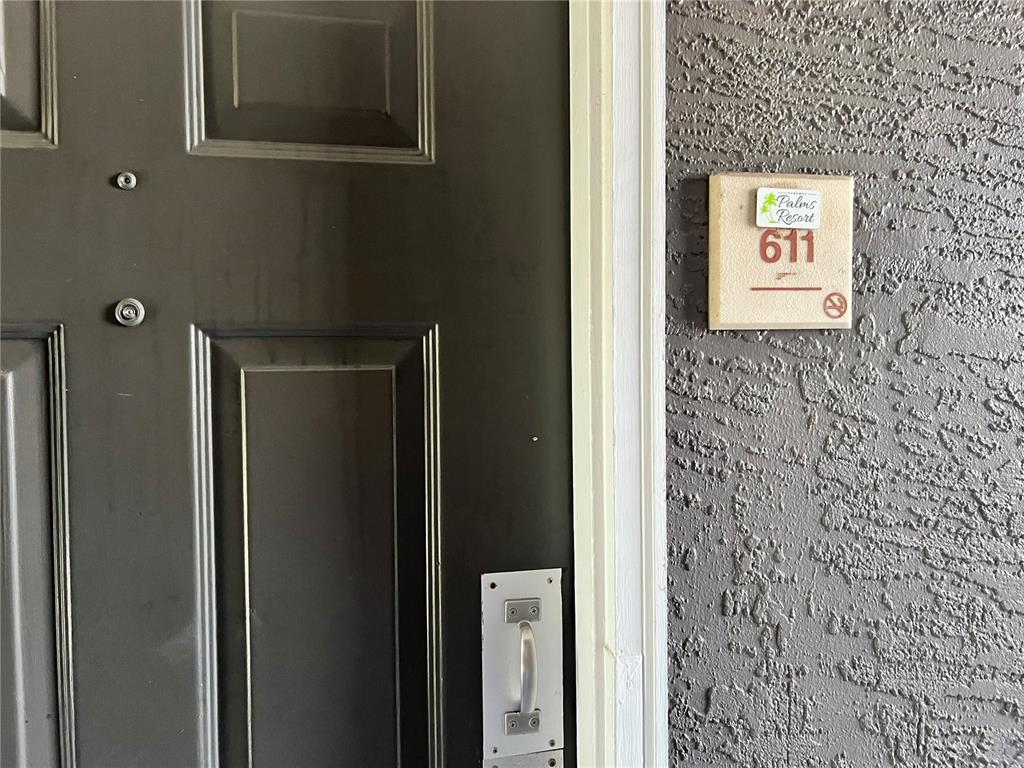 A dark brown door with a silver handle sits next to a room number sign — 3100 PARKWAY BOULEVARD UNIT 611, KISSIMMEE, FL