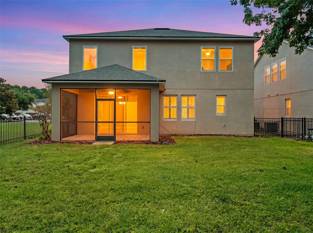 The exterior rear view of a two-story house features a screened-in porch and lawn — 7906 JAILENE DRIVE, WINDERMERE, FL