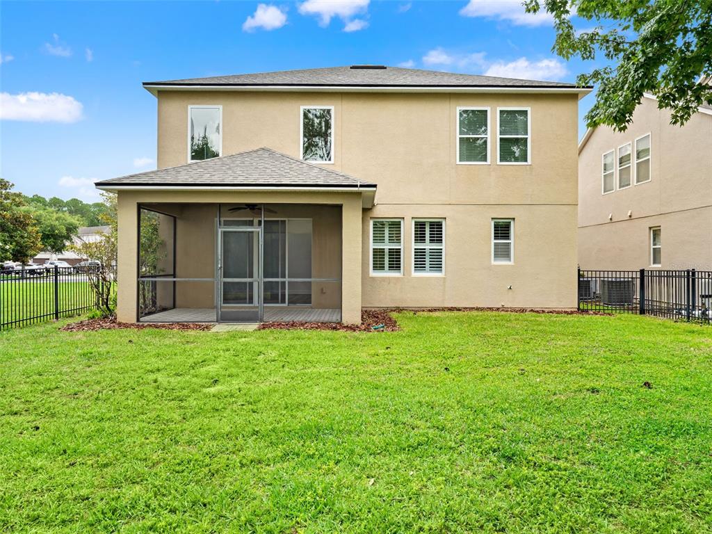 The rear exterior of a two-story house features a screened-in patio and a grassy yard — 7906 JAILENE DRIVE, WINDERMERE, FL
