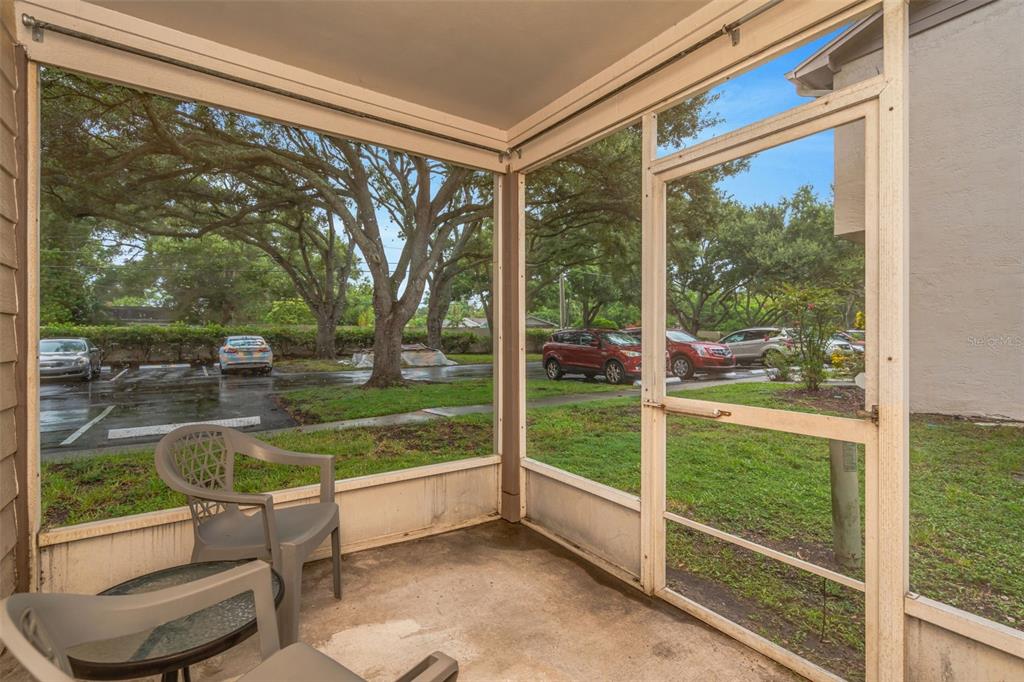 A screened-in patio features a concrete floor, outdoor furniture, and views of a parking lot — 2208 FLETCHERS POINT CIRCLE, TAMPA, FL
