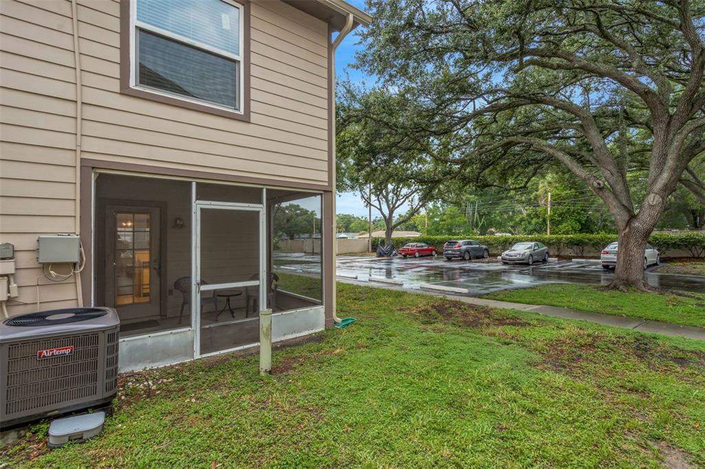 An exterior view of a house with a screened-in patio, an AC unit, and a parking lot — 2208 FLETCHERS POINT CIRCLE, TAMPA, FL