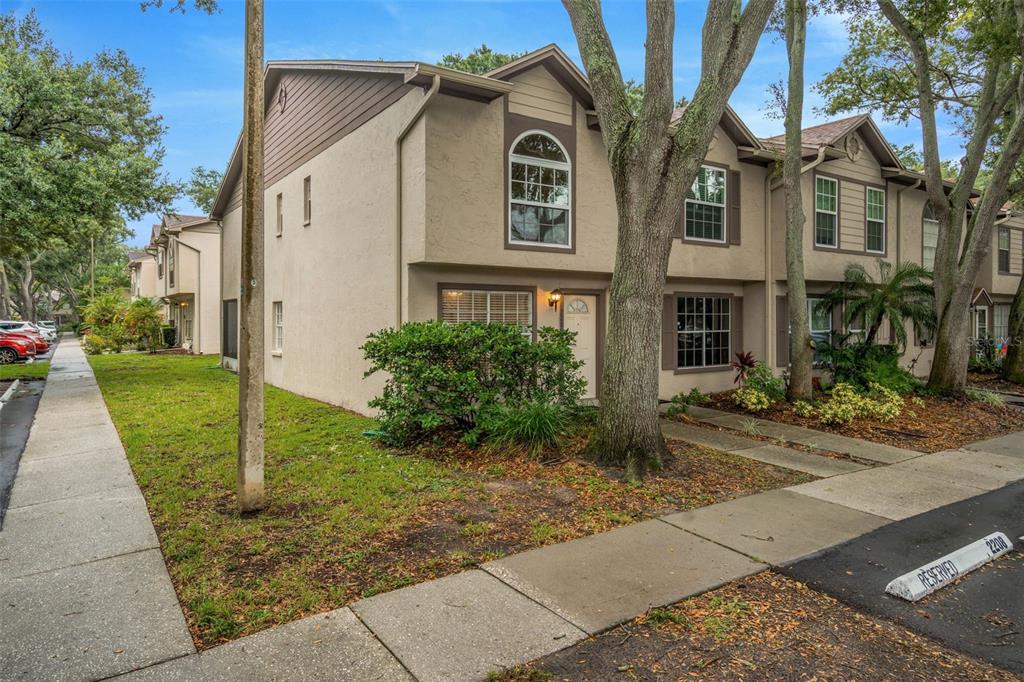 A two-story tan townhouse with a front entrance, arched window, and a reserved parking space — 2208 FLETCHERS POINT CIRCLE, TAMPA, FL