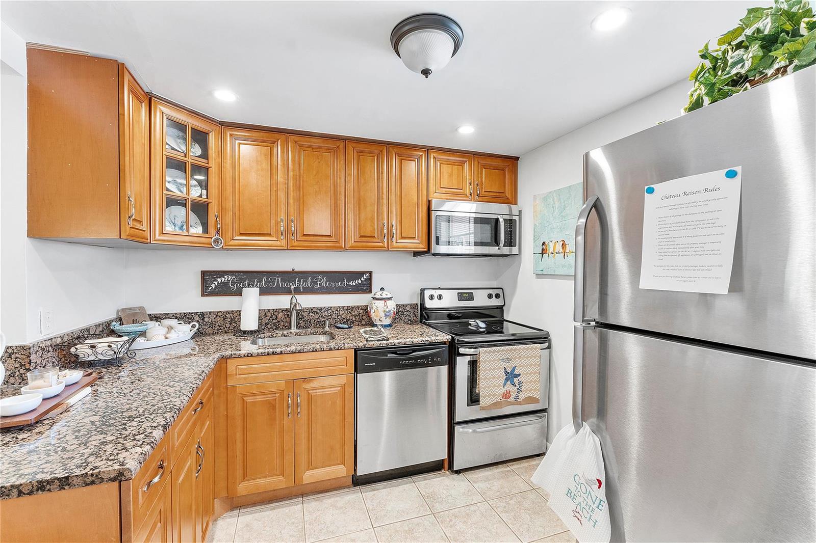 A kitchen with wood cabinets, granite countertops, stainless steel appliances, and tile flooring — 441 NW 76th Avenue # 101, Margate FL 33063, MARGATE, FL