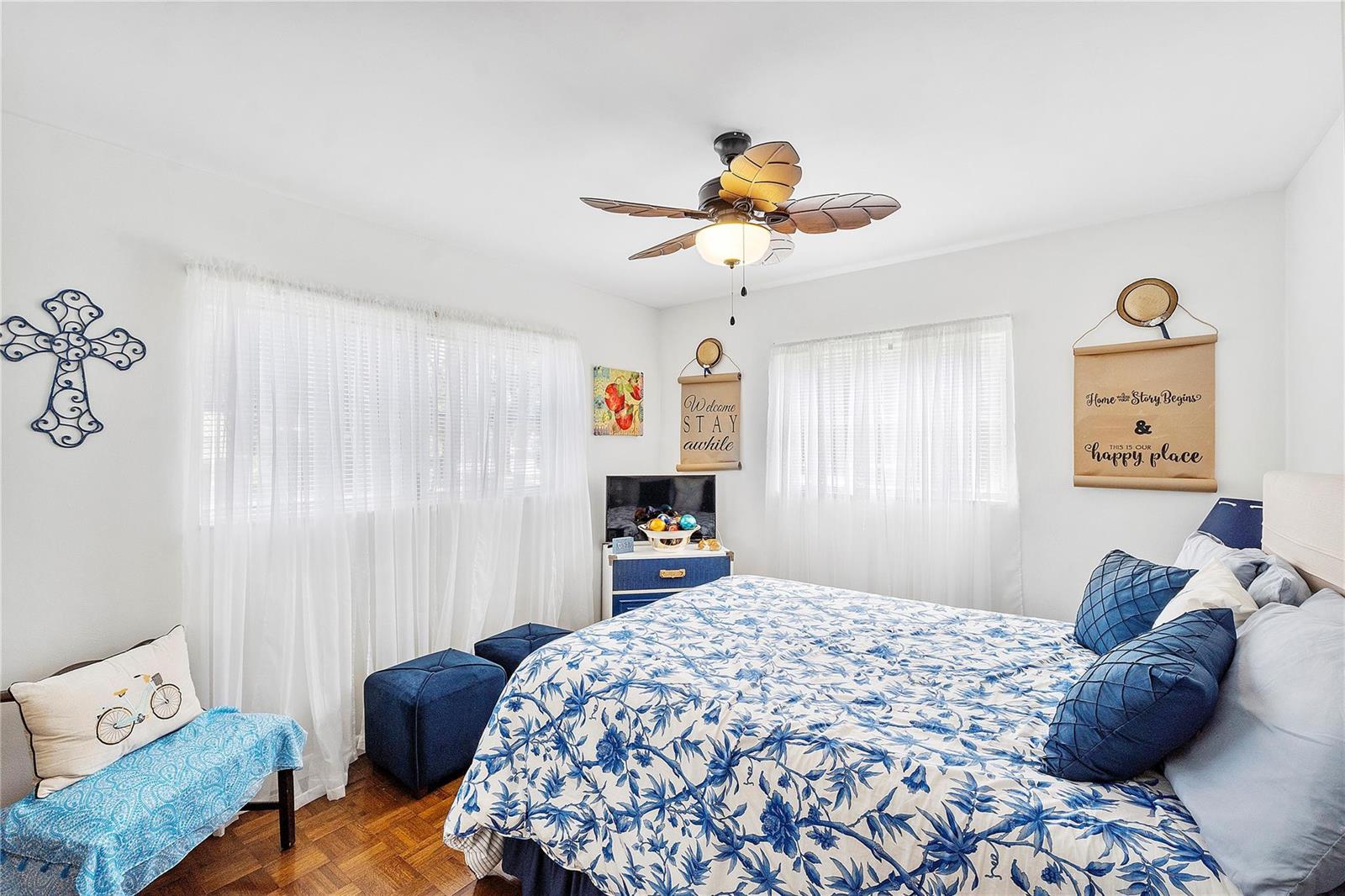 A bedroom features a blue and white floral bedspread, a ceiling fan, and white curtains — 441 NW 76th Avenue # 101, Margate FL 33063, MARGATE, FL