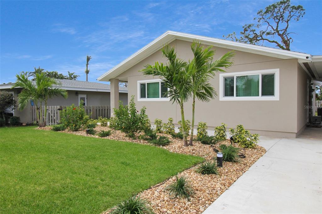 A tan single-story house features a landscaped front yard with palm trees and rock mulch — 5824 WILDWOOD AVENUE, SARASOTA, FL