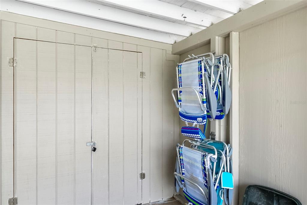 A storage closet with double doors and wall-mounted racks holding folded beach chairs — 5824 WILDWOOD AVENUE, SARASOTA, FL