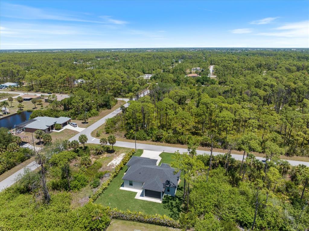 An aerial view shows a single-story house with a dark roof surrounded by dense forest — 12123 FEDERAL AVENUE, PORT CHARLOTTE, FL
