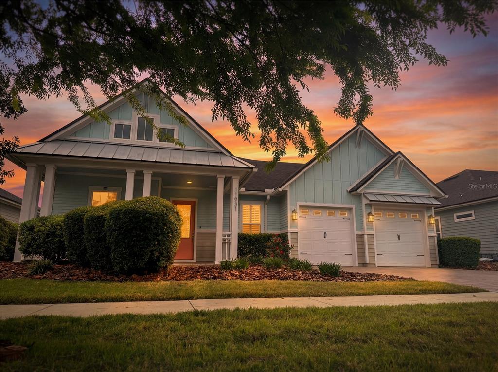 A light blue house with a front porch, two garage doors, and a sunset sky — 11931 SW 32ND LANE, GAINESVILLE, FL
