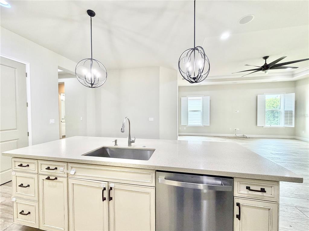 A kitchen island with a stainless steel sink and dishwasher sits before an open living area — 11931 SW 32ND LANE, GAINESVILLE, FL