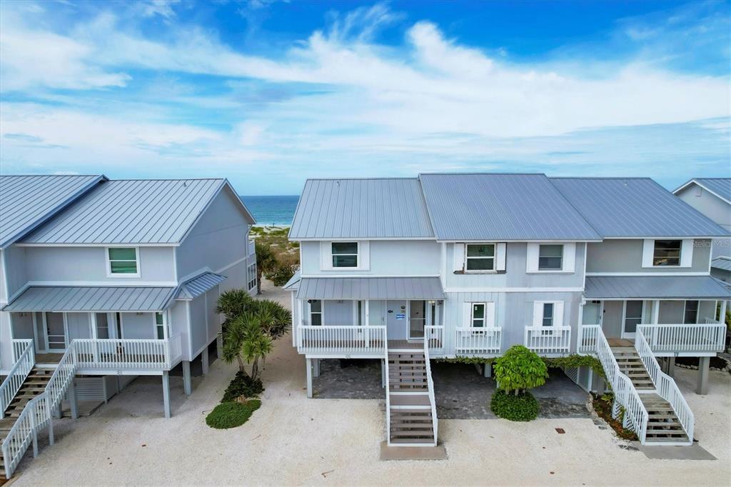An aerial view of three elevated, light blue beach houses with metal roofs near the ocean — 420 GULF BOULEVARD UNIT 20, BOCA GRANDE, FL