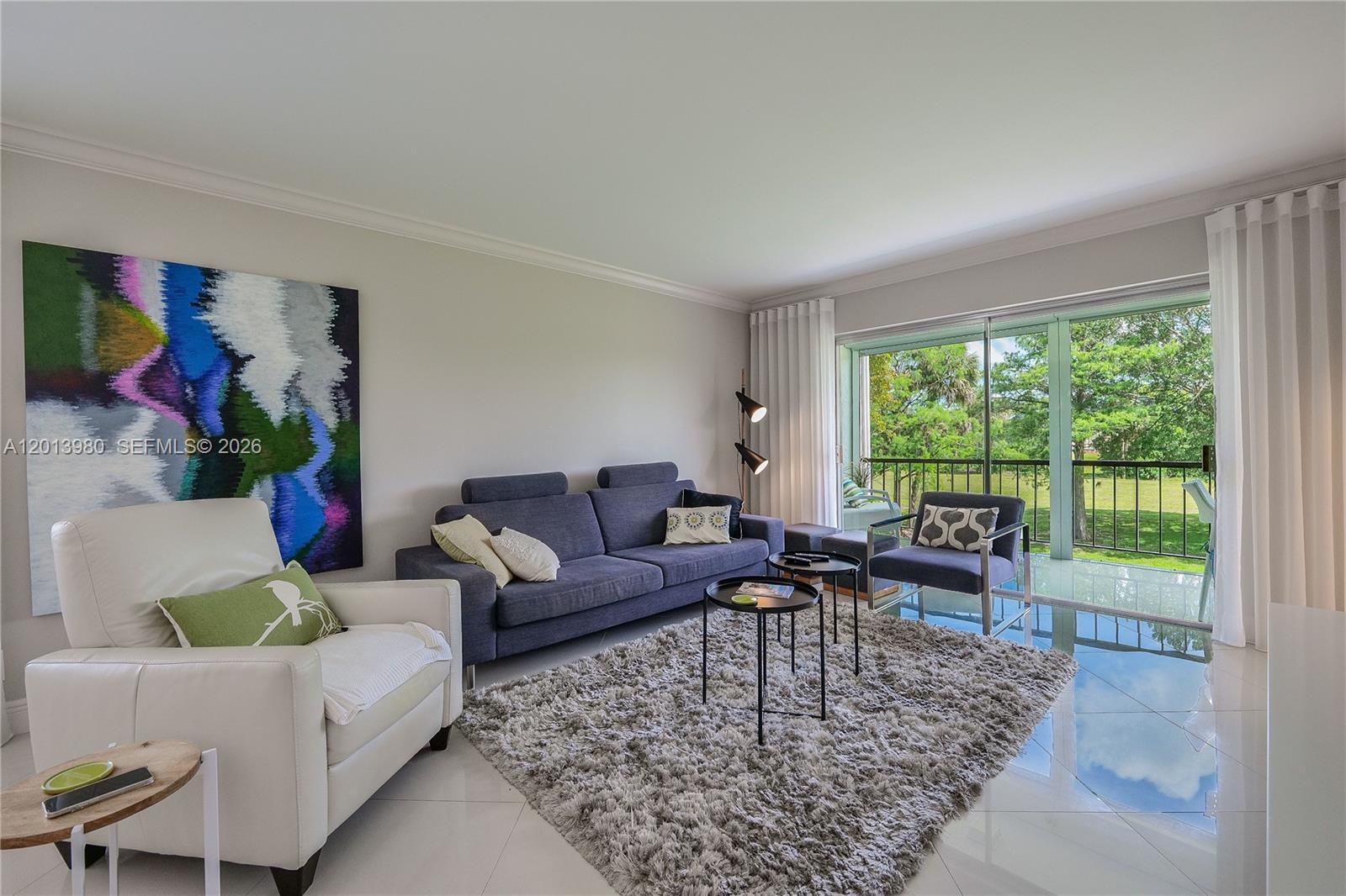 A living room features a gray sofa, white armchair, shag rug, and a sliding glass door — 6200 NW 44th St # 301, Lauderhill FL 33319, LAUDERHILL, FL