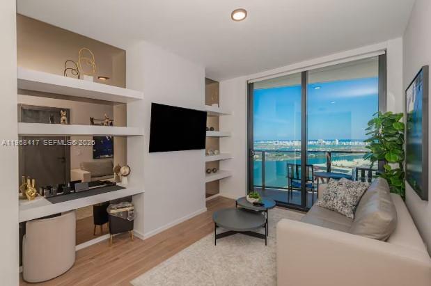 A modern living room features a built-in desk, shelving, a sofa, and a balcony view — 398 NE 5th St # 3511, Miami FL 33132, MIAMI, FL