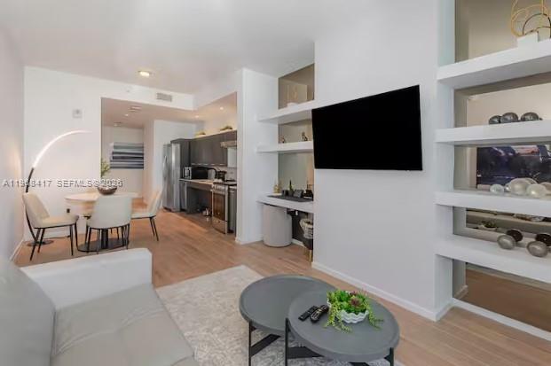 A modern living room and kitchen area with light wood flooring and white shelving — 398 NE 5th St # 3511, Miami FL 33132, MIAMI, FL