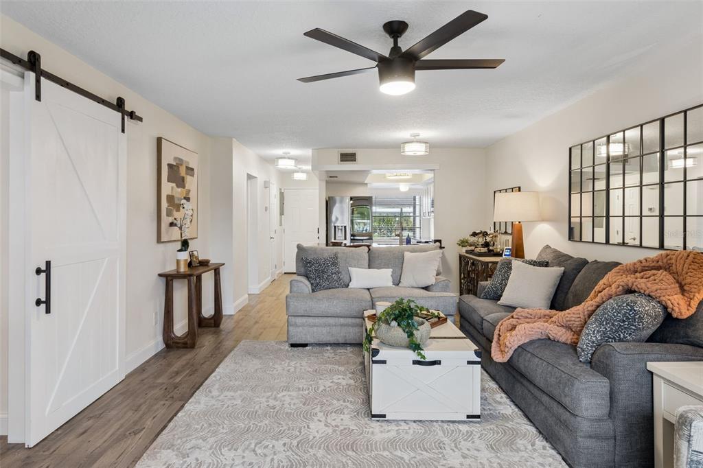 A living room features a gray sofa, a white coffee table, and a sliding barn door — 5157 SILENT LOOP UNIT 110, NEW PORT RICHEY, FL