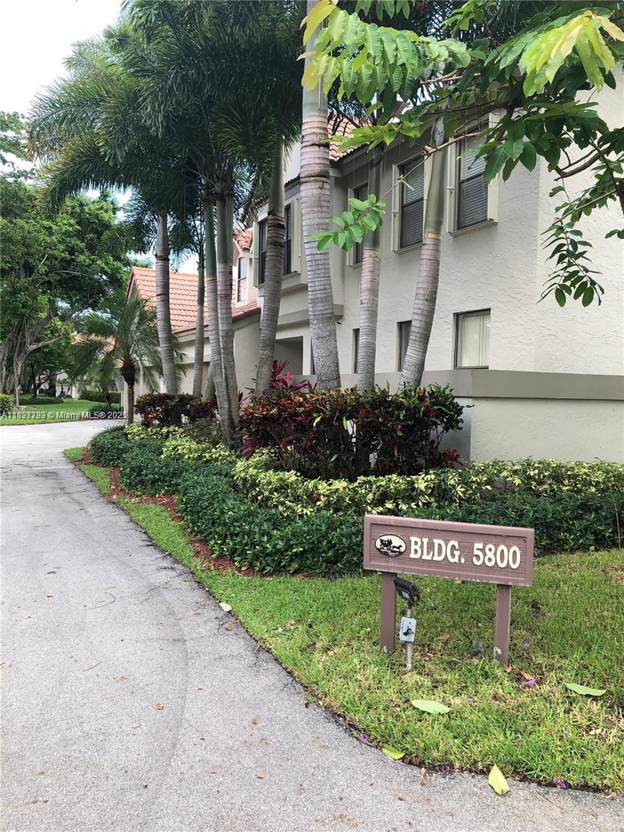 A two-story building with a sign labeled BLDG. 5800 stands behind palm trees and landscaping — 5800 Coach House Cir, Boca Raton FL 33486, BOCA RATON, FL