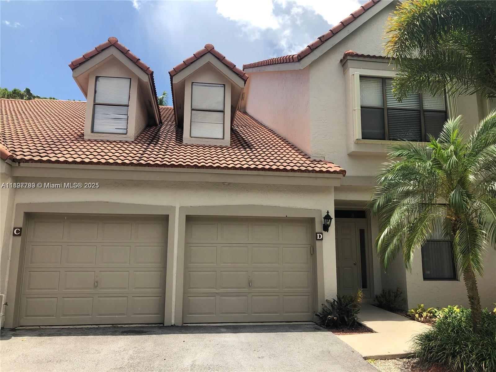 The exterior of a two-story townhouse features two garage doors, dormer windows, and a tiled roof — 5800 Coach House Cir, Boca Raton FL 33486, BOCA RATON, FL